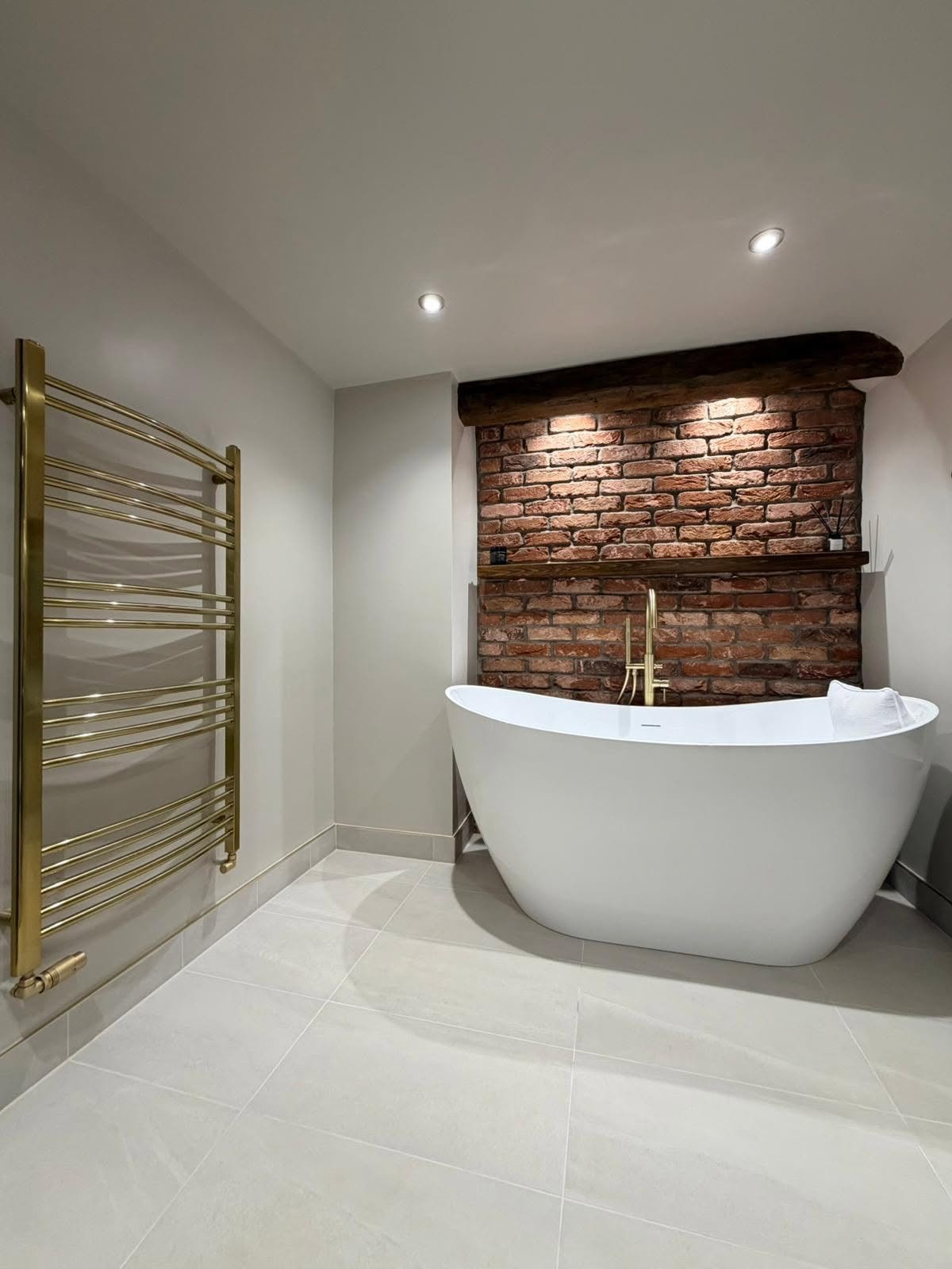 Freestanding bath installation with exposed brick feature wall in a Derbyshire bathroom renovation
