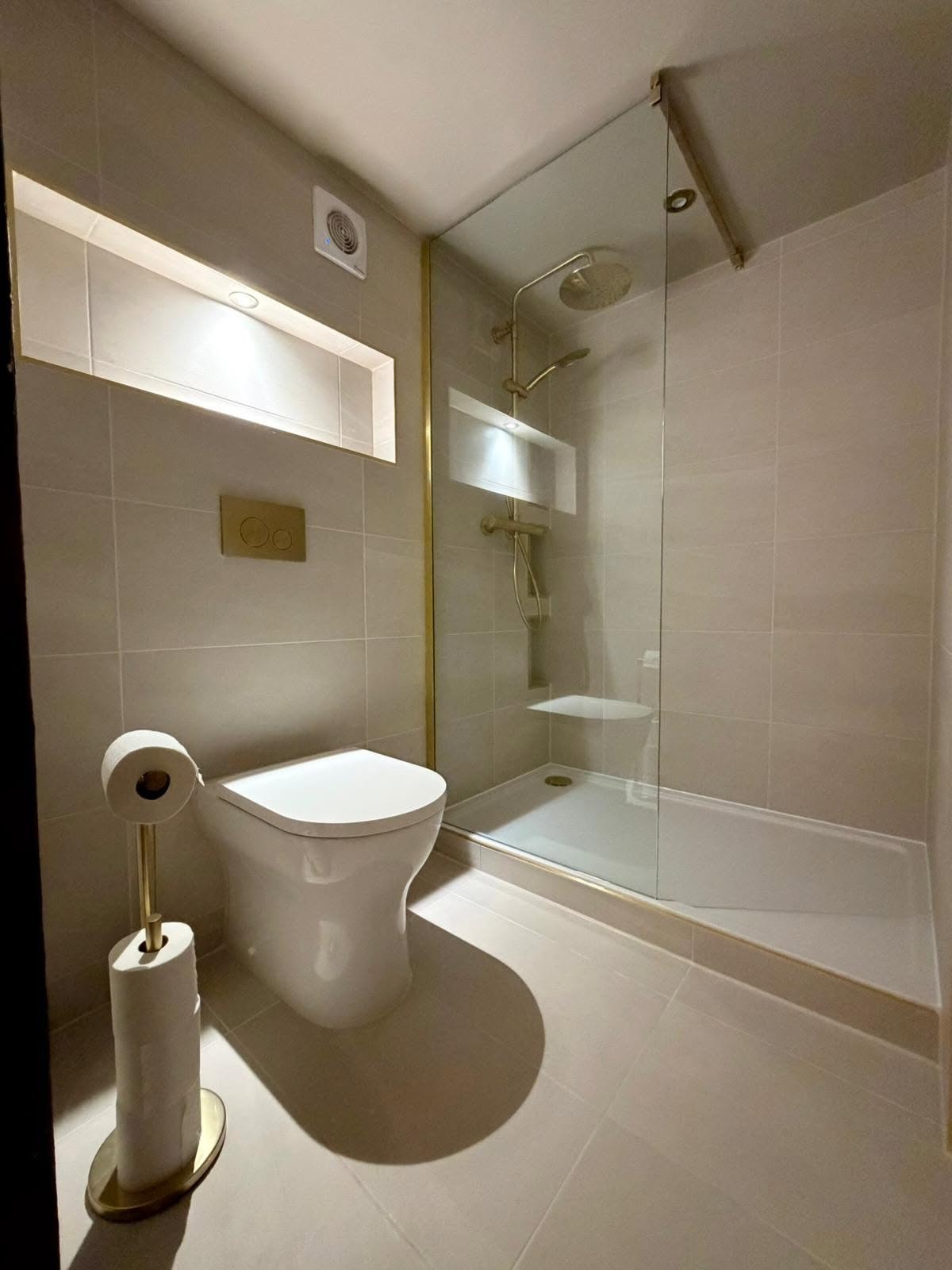 En-suite bathroom renovation with shower niche, toilet and brushed brass fittings