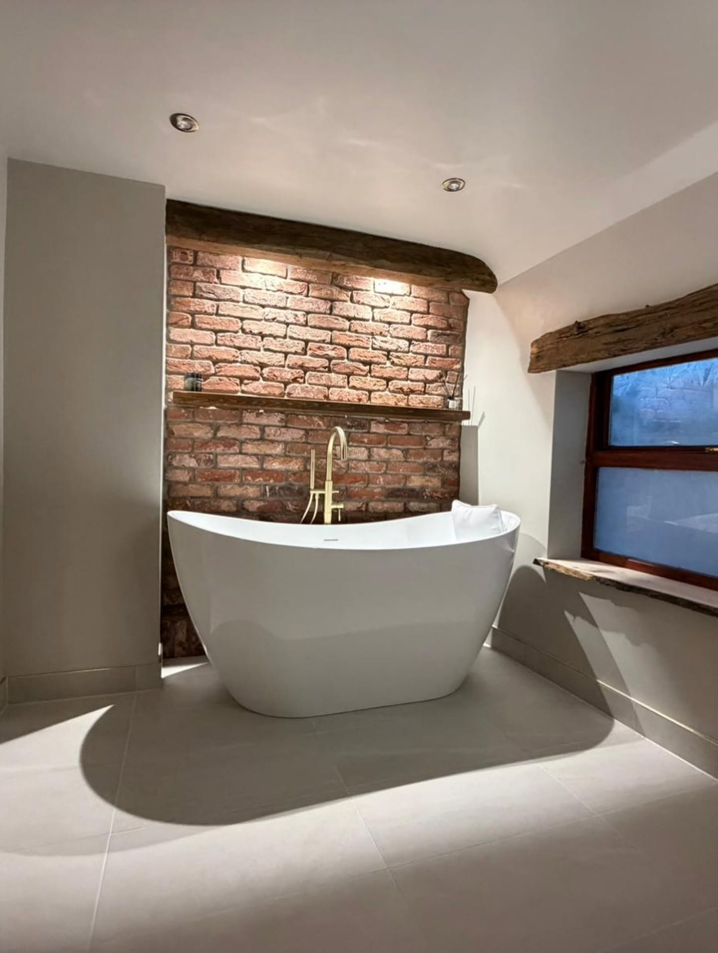 Full rustic bathroom remodel in Derbyshire with freestanding bath and exposed brick wall