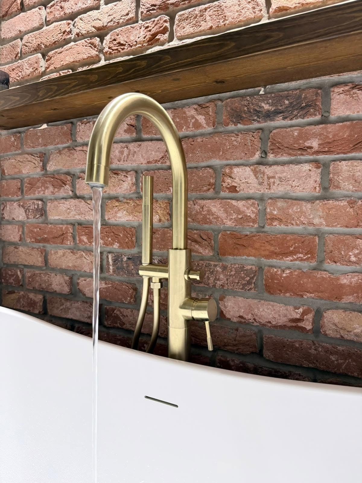 Premium bathroom finishing with brushed brass bath taps and coordinated fittings